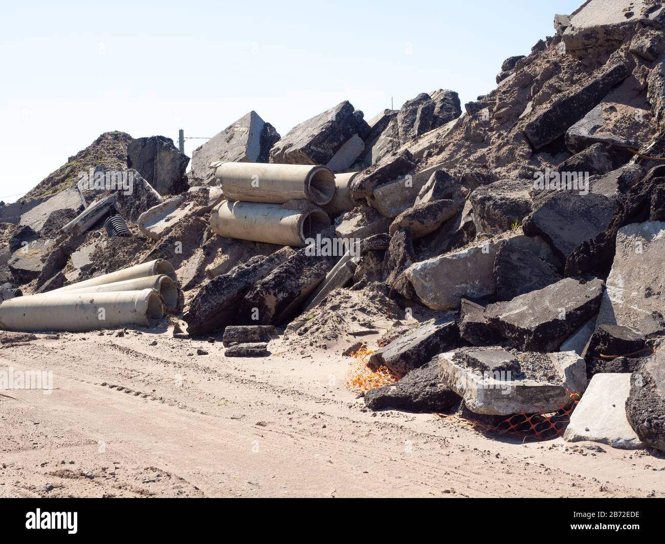 Muro di pavimentazione e pavimentazione di asfalto e cemento, tubi per fognature in calcestruzzo, detriti di parcheggio e cordoli di cemento, presso il cantiere di demolizione stradale Foto Stock