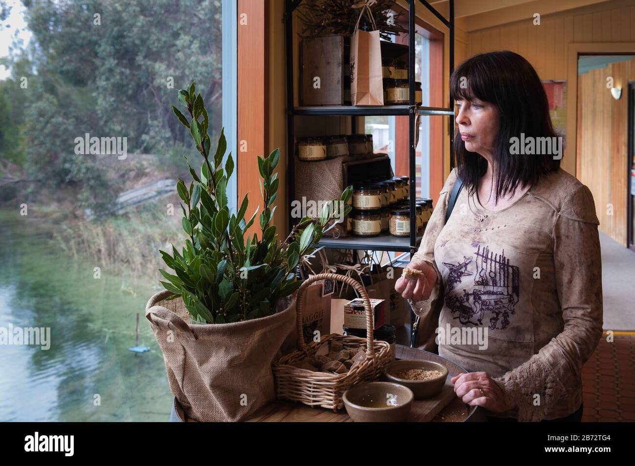 Femminile turistica degusta le cimes aromatiche con i pezzi di pane biologico mentre si affaccia sullo stagno nel giardino della Fattoria Pheasant, Barossa Valley. Foto Stock Femminile turistica degusta le cimes aromatiche con i pezzi di pane biologico mentre si affaccia sullo stagno nel giardino della Fattoria Pheasant, Barossa Valley. Foto Stock