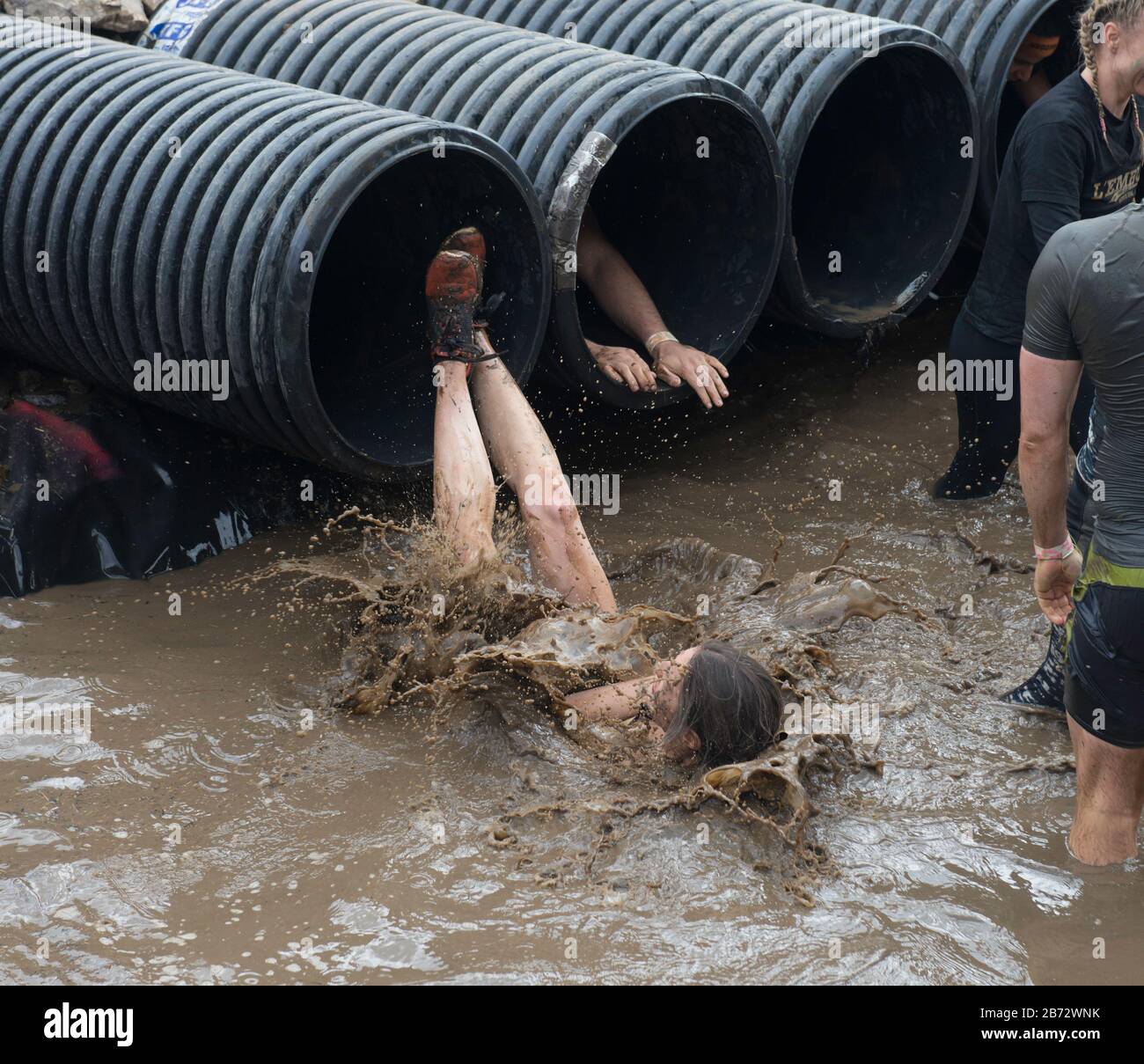 Difficile Mudder ostacolo corso: Partecipanti affrontare l'ostacolo Shawshanked caduta in acqua fredda fangosa Foto Stock