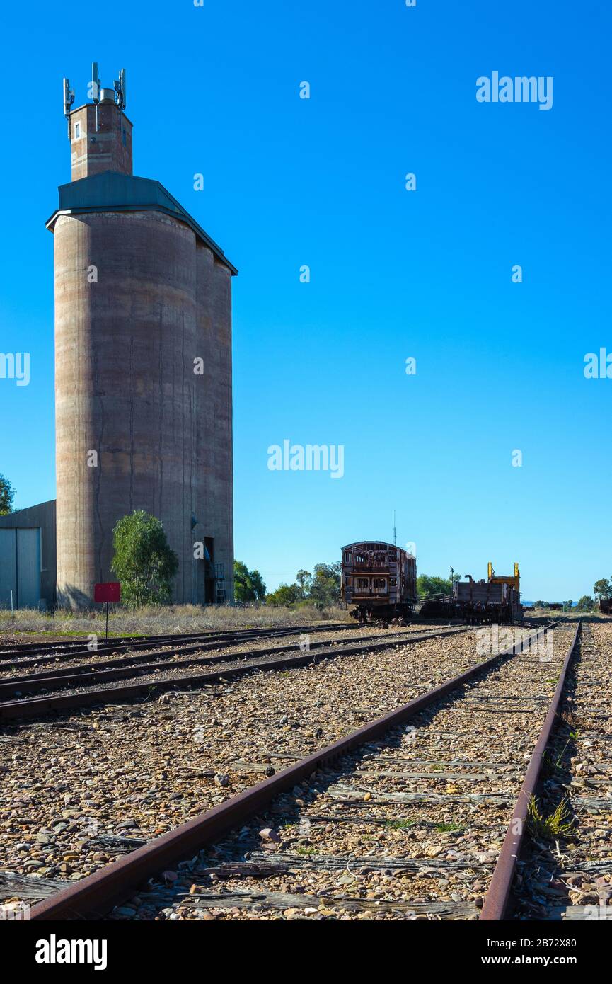 I vecchi binari ferroviari storici che portano a nord lontano da Quorn in Australia del Sud, oltrepassano un vecchio silo, un capannone merci e un paio di carrozze ferroviarie d'epoca. Foto Stock