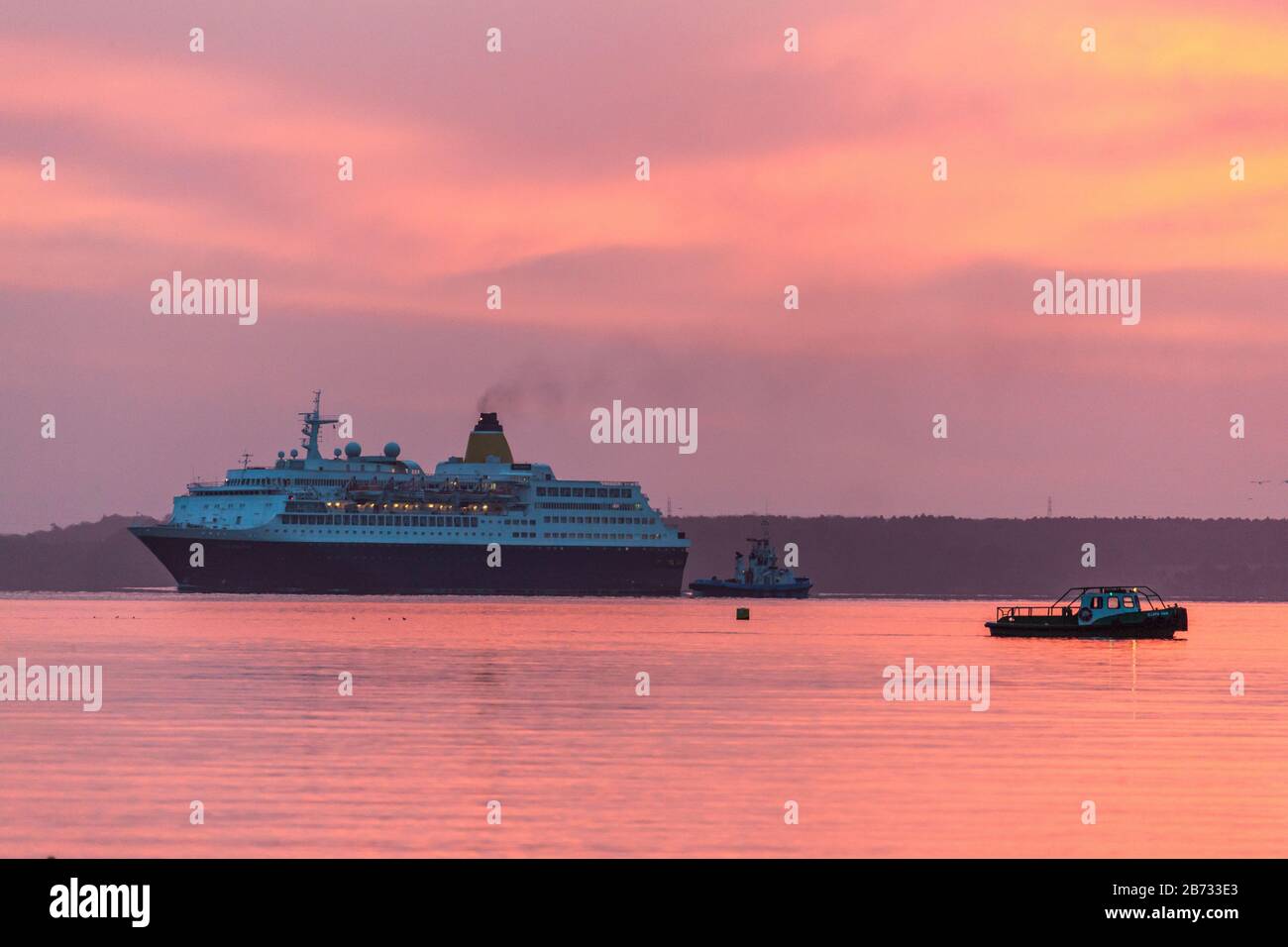 Cobh, Cork, Irlanda. 13 Marzo 2020 . Lavorare in barca Geata Bán e tirare Gerry o’Sullivan a portata di mano per assistere la nave da crociera Saga Sapphire mentre si fa strada fino al porto prima dell'alba. Con 752 passeggeri a bordo, era originariamente destinata ad ormeggiare a Cobh, ma con nuove misure in atto per combattere la diffusione di Covid-19 il suo ormeggio fu cambiato in Ringaskiddy, Co. Cork, Irlanda. - Credito; David Creedon / Alamy Live News Foto Stock