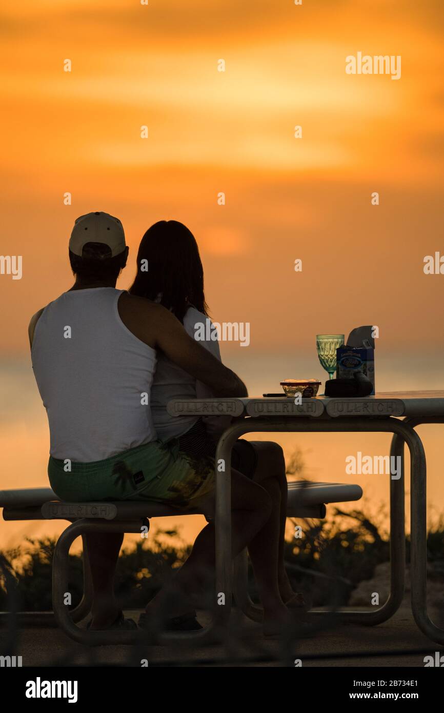 Scena romantica di una coppia godendosi lo spettacolare tramonto arancione attraverso l'Oceano Indiano a Osprey Bay nell'Australia Occidentale. Foto Stock