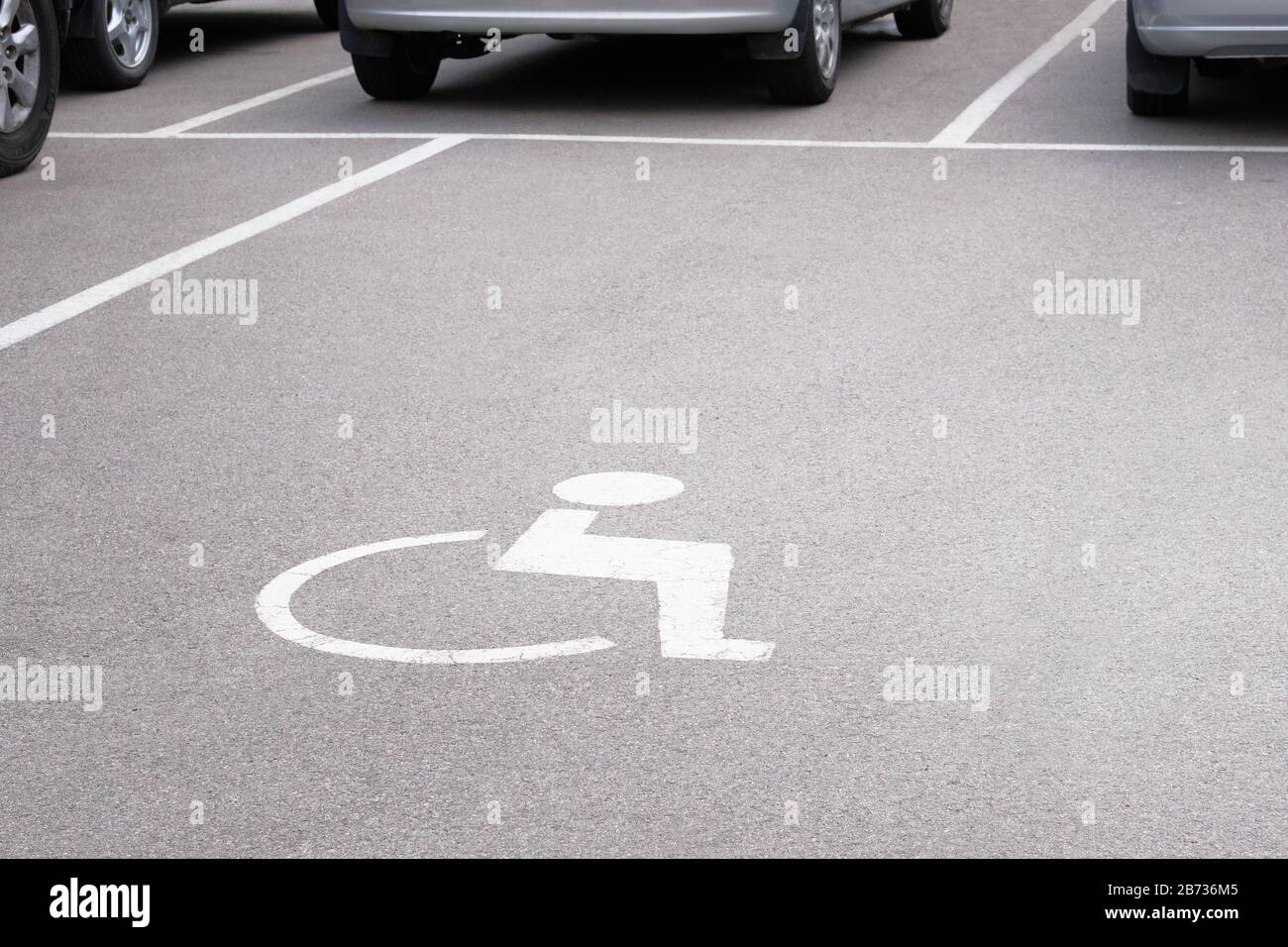 Contrassegno di permesso posto auto per disabili sulla strada asfaltata. Simbolo di segnaletica stradale su strada. Foto Stock