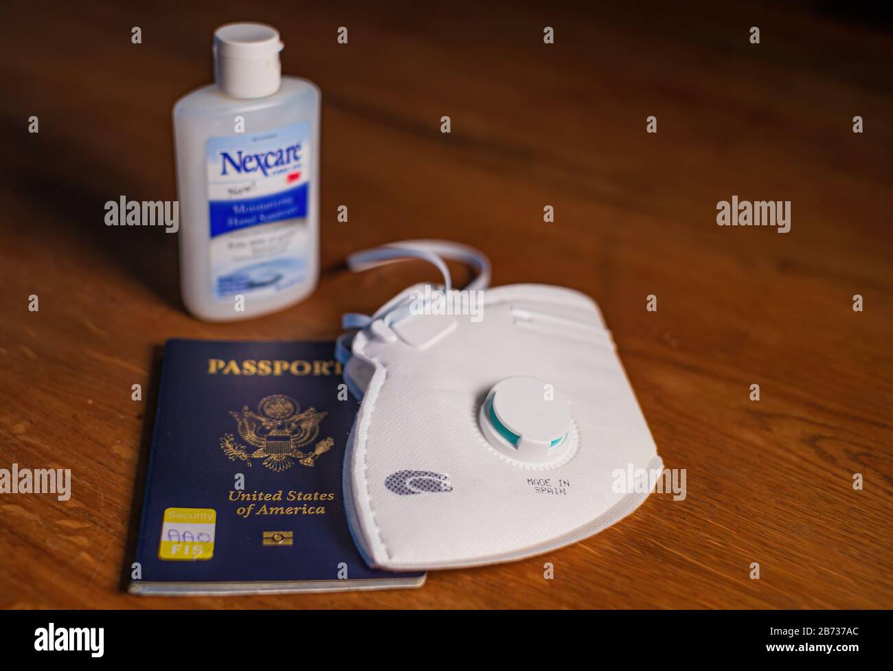 Boston, USA - 13 Marzo 2020: Primo piano di maschera, passaporto americano e desinfattante sul tavolo pronto per il viaggio in tempi di Pandamic Coronavirus. Foto Stock