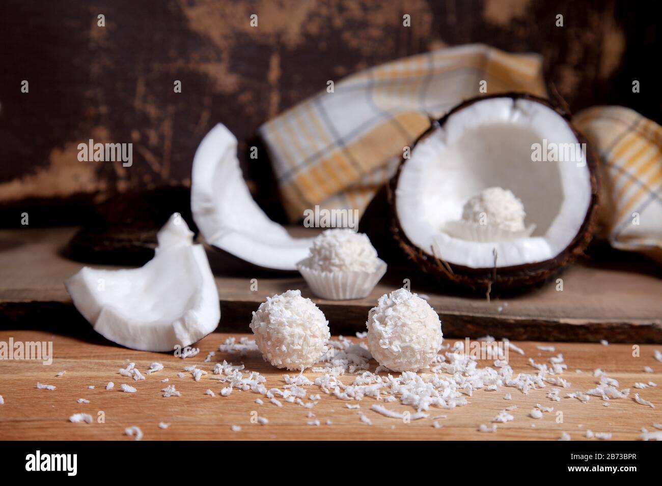 Primo piano di cocco con polpa bianca, scaglie di cocco e tartufi di cocco dolce al cioccolato. Guscio di cocco, fiocchi di cocco, piccoli pezzi di dado schiantato, co Foto Stock