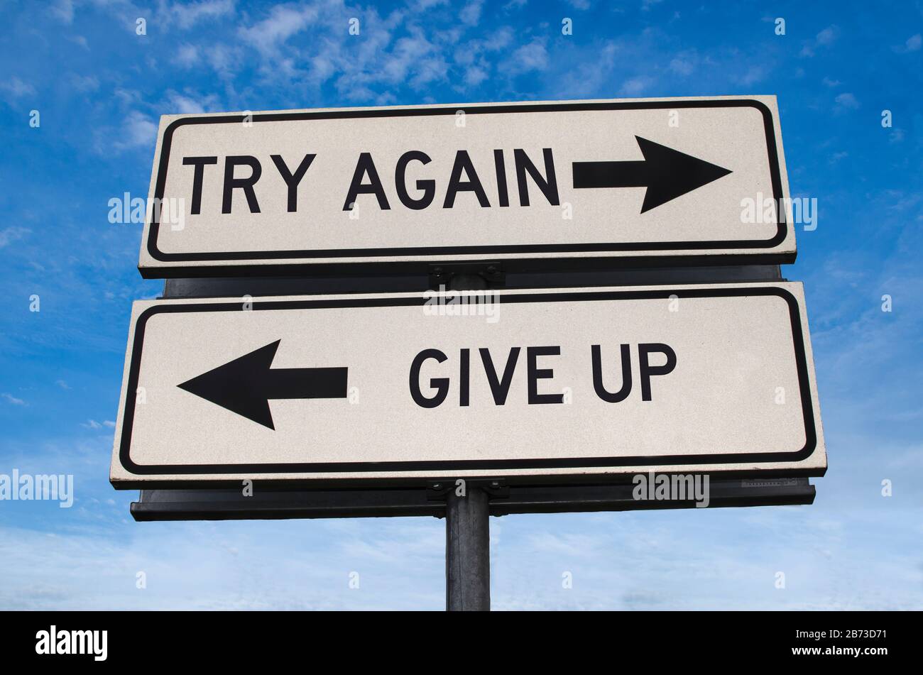 Riprova vs. Give up. Bianco due cartelli stradali con freccia su palo di metallo con parola. Strada direzionale. Cartello stradale crocevia, due frecce. Sfondo blu Foto Stock