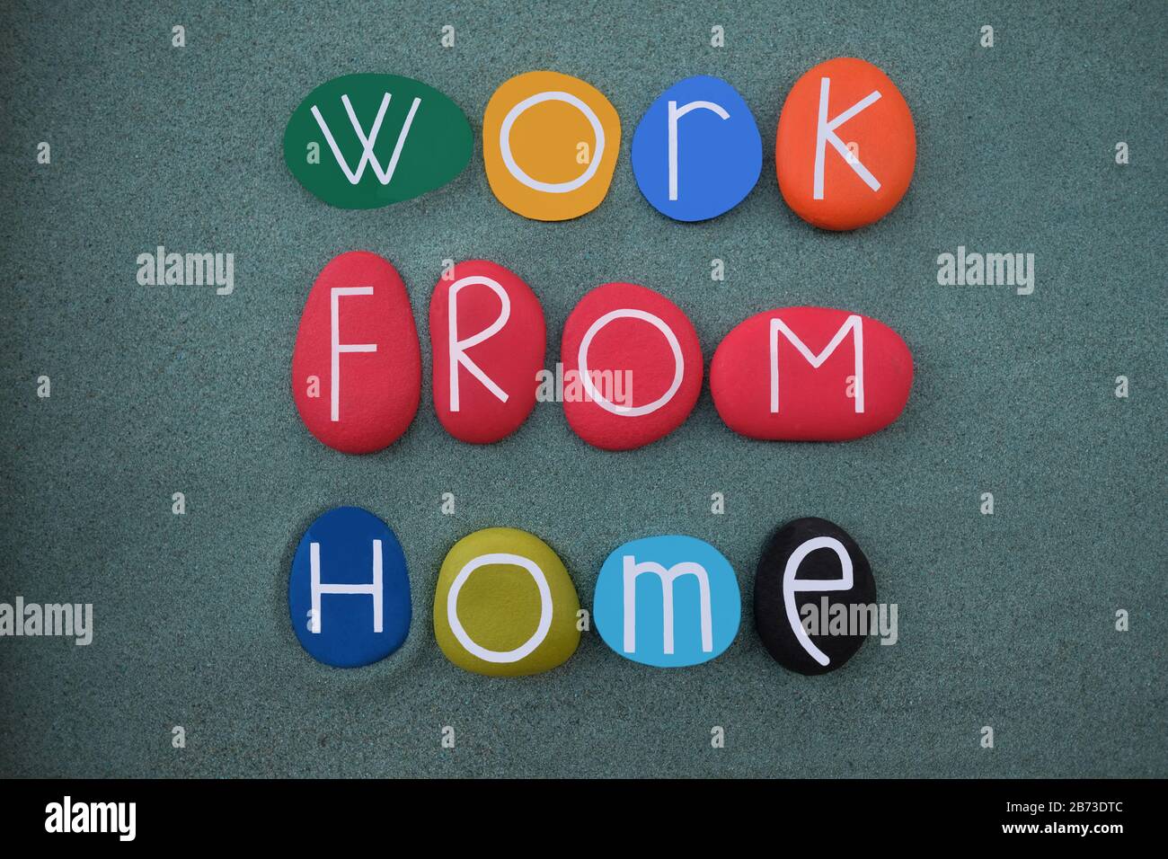 Lavoro da casa, slogan moderno per una vita intelligente composta da lettere in pietra multicolore su sabbia verde Foto Stock