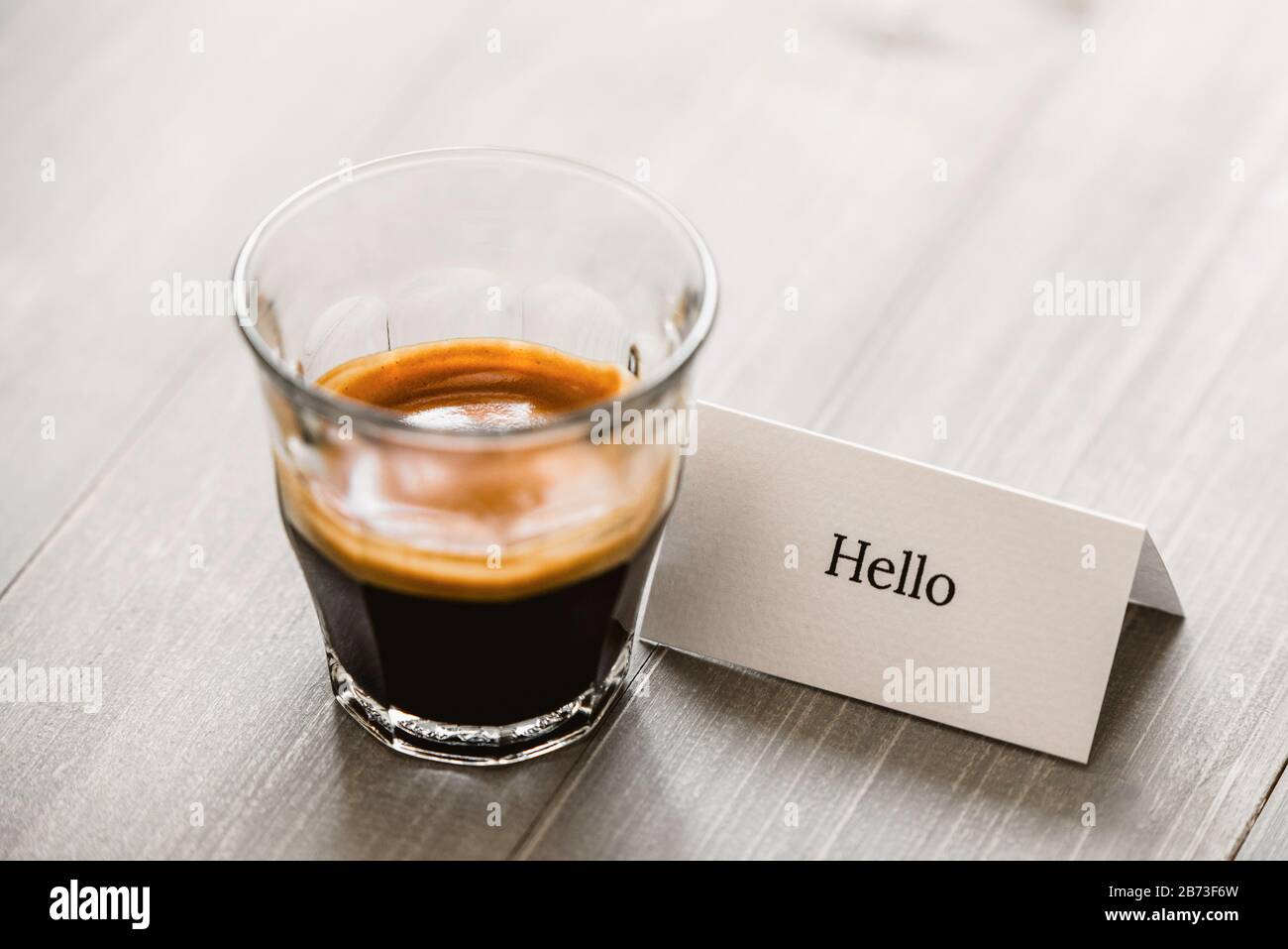 Caffè espresso appena preparato espresso in vetro sul tavolo di legno con biglietto d'auguri Foto Stock