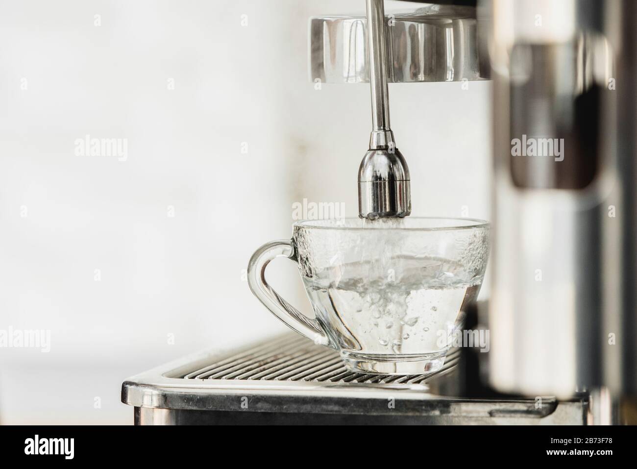 Acqua calda dalla macchina per il caffè che scorre nella tazza per la preparazione di Americano Foto Stock