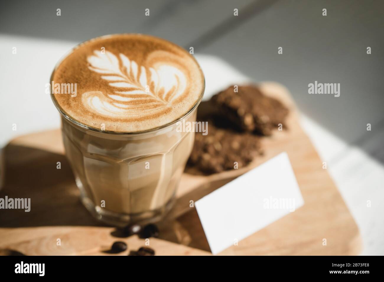 Caffè cappuccino appena preparato con una bella arte del latte su un piatto di legno pronto a bere Foto Stock