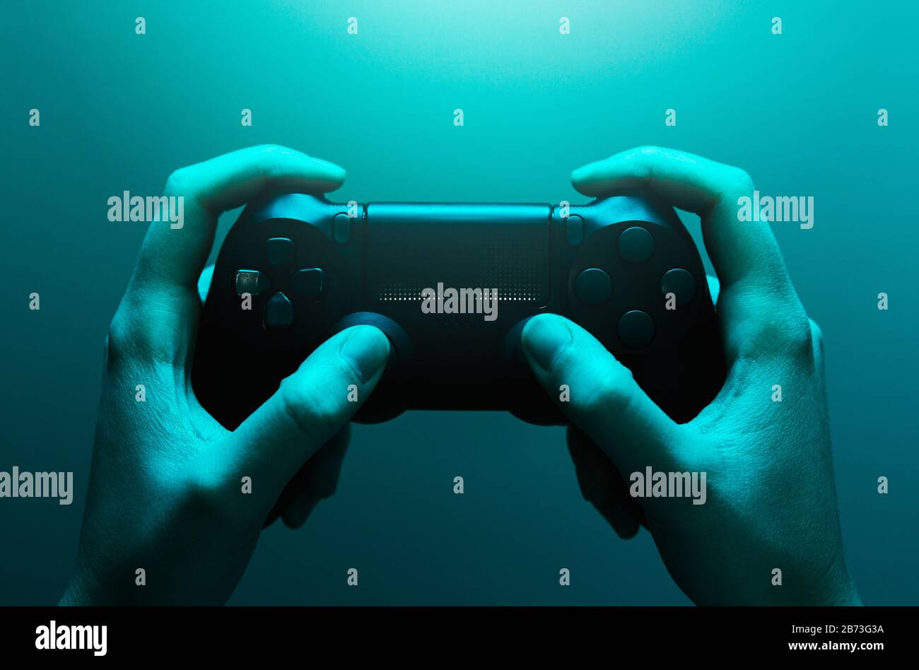 Foto di scorta delle mani che tengono un gamepad nero con una luce blu Foto Stock
