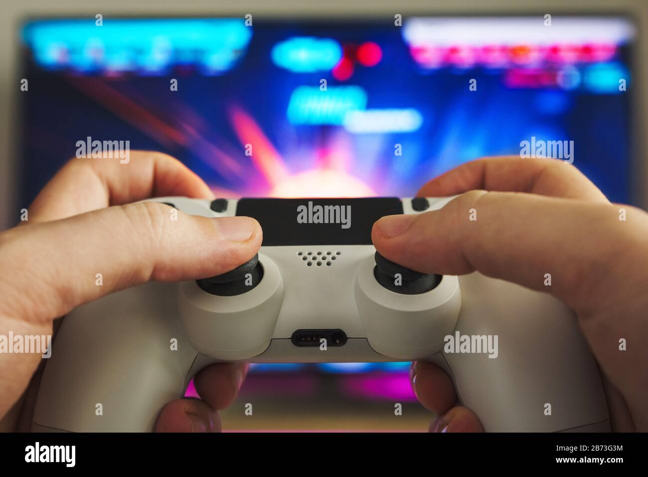 Foto di stock di alcune mani con un gamepad che gioca un gioco sparatutto sulla console di gioco Foto Stock
