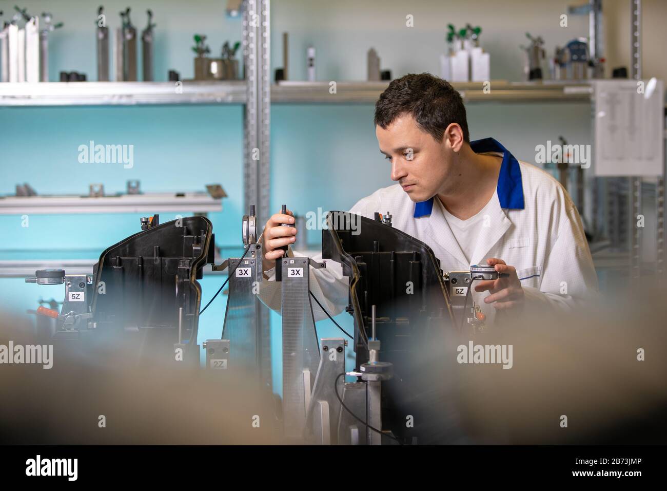 L'ingegnere misura i componenti in plastica per la produzione di luci per l'industria automobilistica in una fabbrica su una macchina digitale 3D Foto Stock