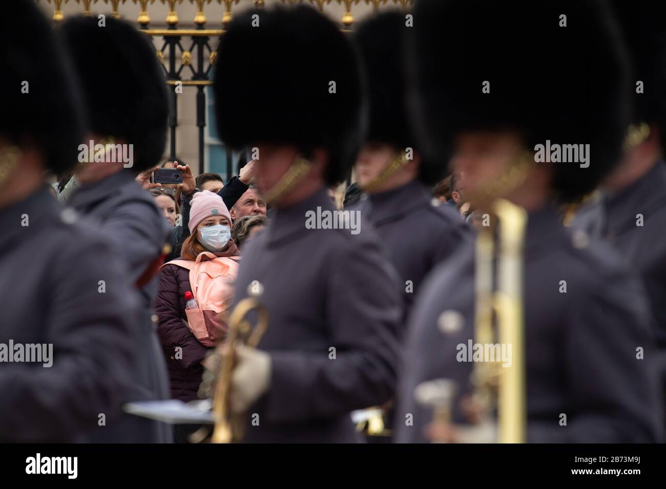 Una donna che indossa una maschera protettiva per il viso guarda la cerimonia Del Cambio della Guardia fuori Buckingham Palace, Londra, il giorno dopo che il primo ministro ha detto che Covid-19 'è la peggiore crisi di salute pubblica per una generazione', E il più alto scienziato del governo ha avvertito che fino a 10,000 persone nel Regno Unito sono già infettate. Foto PA. Data Foto: Venerdì 13 Marzo 2020. Vedi la storia PA SALUTE Coronavirus. Il credito per le foto deve essere: Dominic Lipinski/PA Wire Foto Stock
