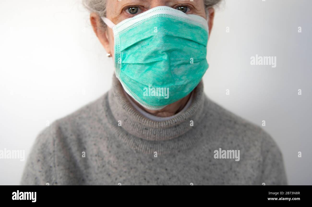 Donna anziana che indossa una maschera chirurgica protettiva (posata con il modello) Foto Stock