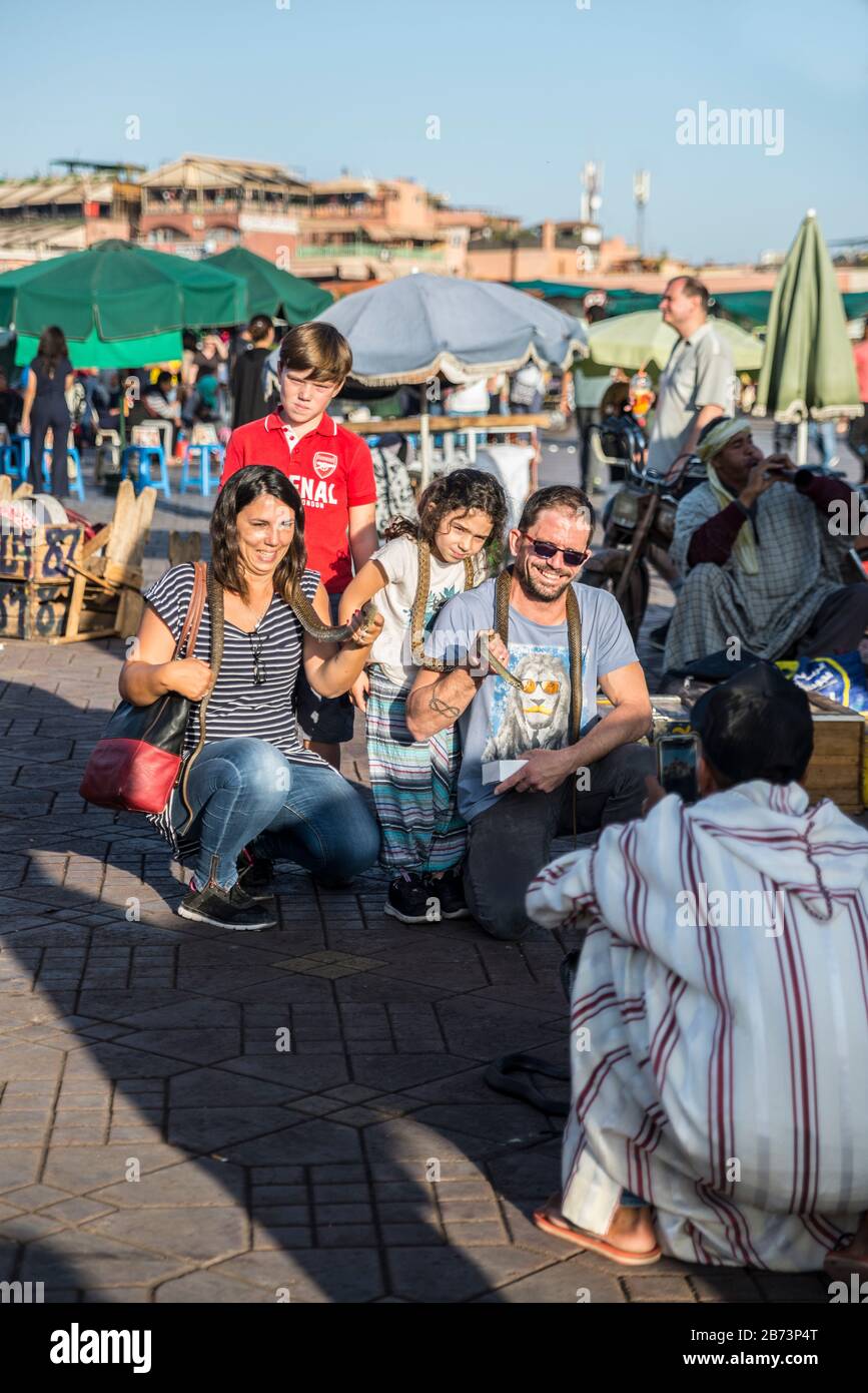 Famiglia dopo aver scattato foto con serpenti, piazza Jemaa el fna, Marrakech, Marocco Foto Stock