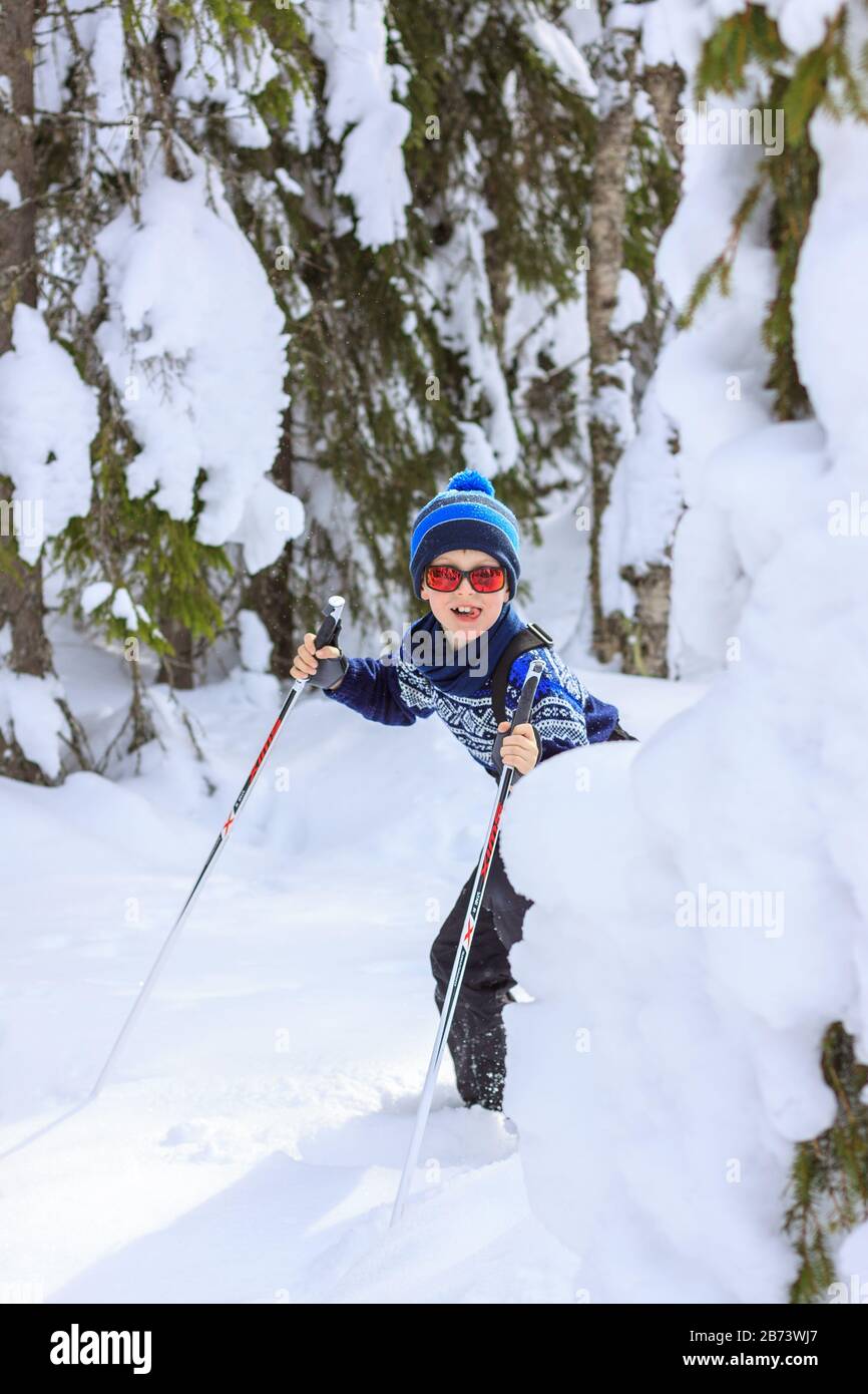 Giovane ragazzo che sbirciava da dietro pesanti alberi ricoperti di neve,  con espressione giocosa e allegra sul suo viso, lingua fuori. Vestito in  maglia Foto stock - Alamy