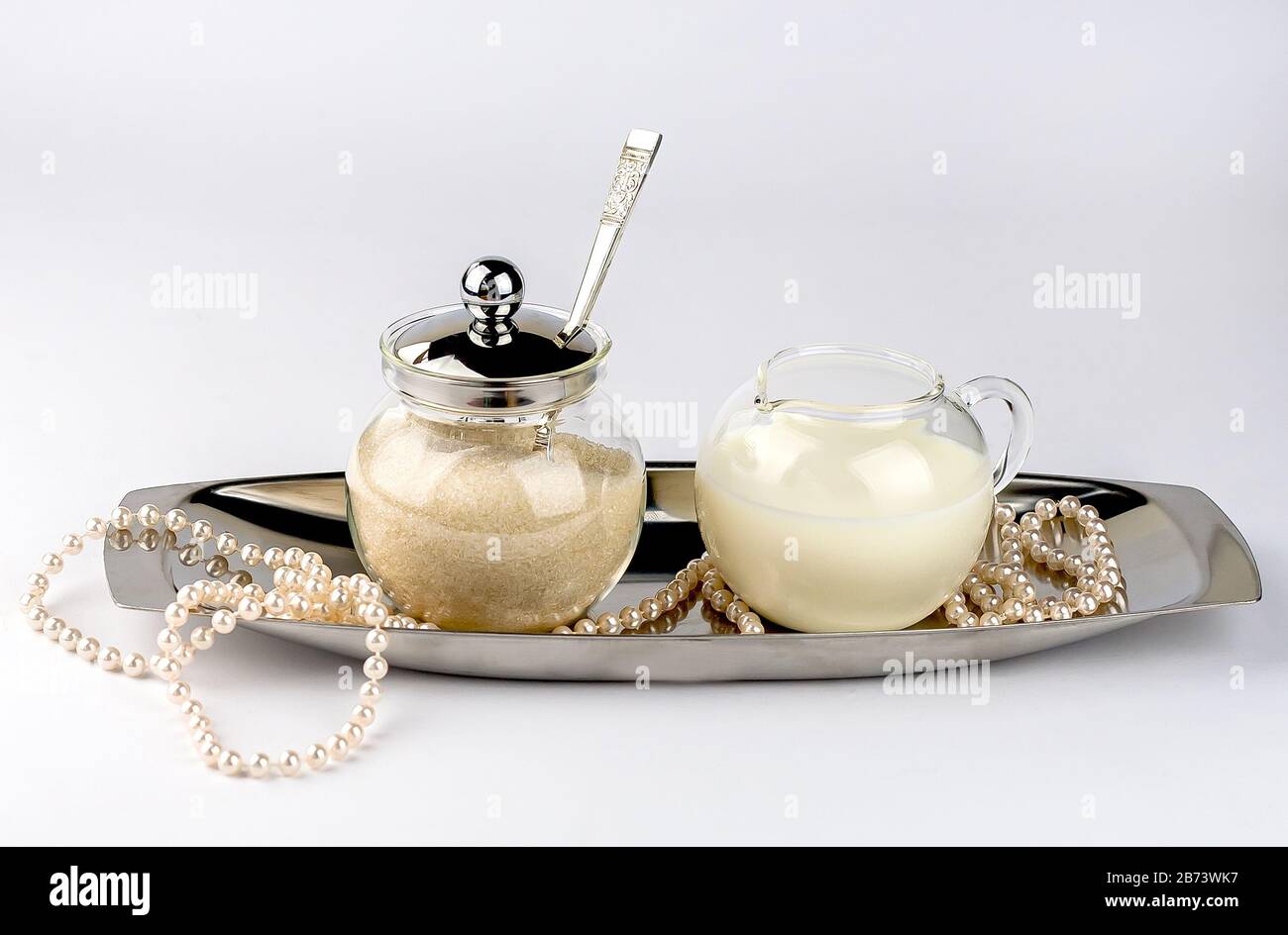 Ciotola di zucchero e milkman su un piatto di servizio d'argento con perline isolate su sfondo bianco. Foto Stock