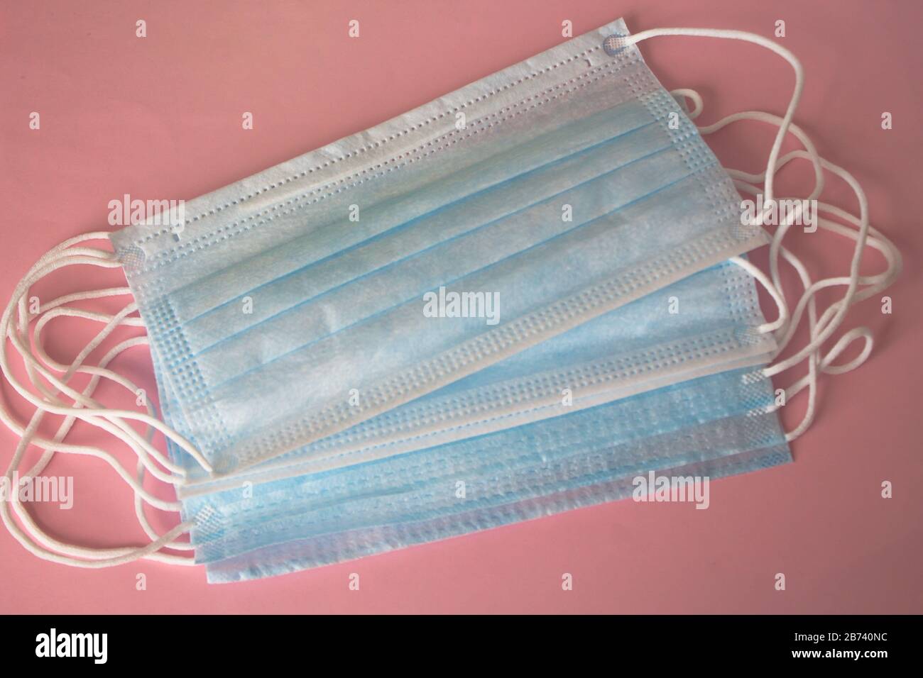 Maschere mediche su sfondo rosa. La disperazione pandemica si diffonde in tutto il mondo. Trattamento medico delle persone infette. Assistenza sanitaria Foto Stock