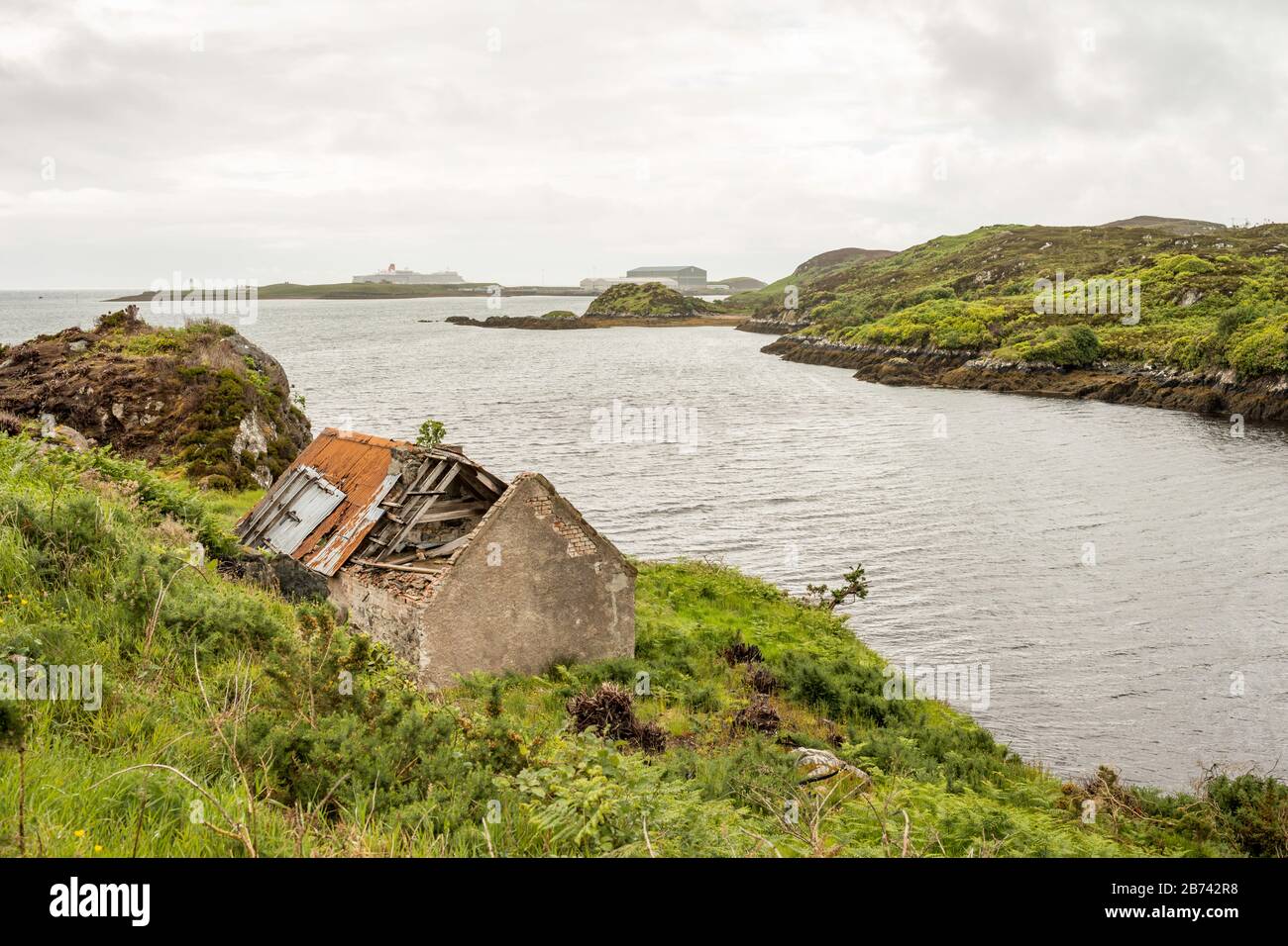 Un cottage abbandonato sulla riva di Stornoway Bay, nei terreni del castello di Lews, Stornoway, Scozia, Regno Unito. Nave Cunard la regina Elisabetta può essere visto. Foto Stock