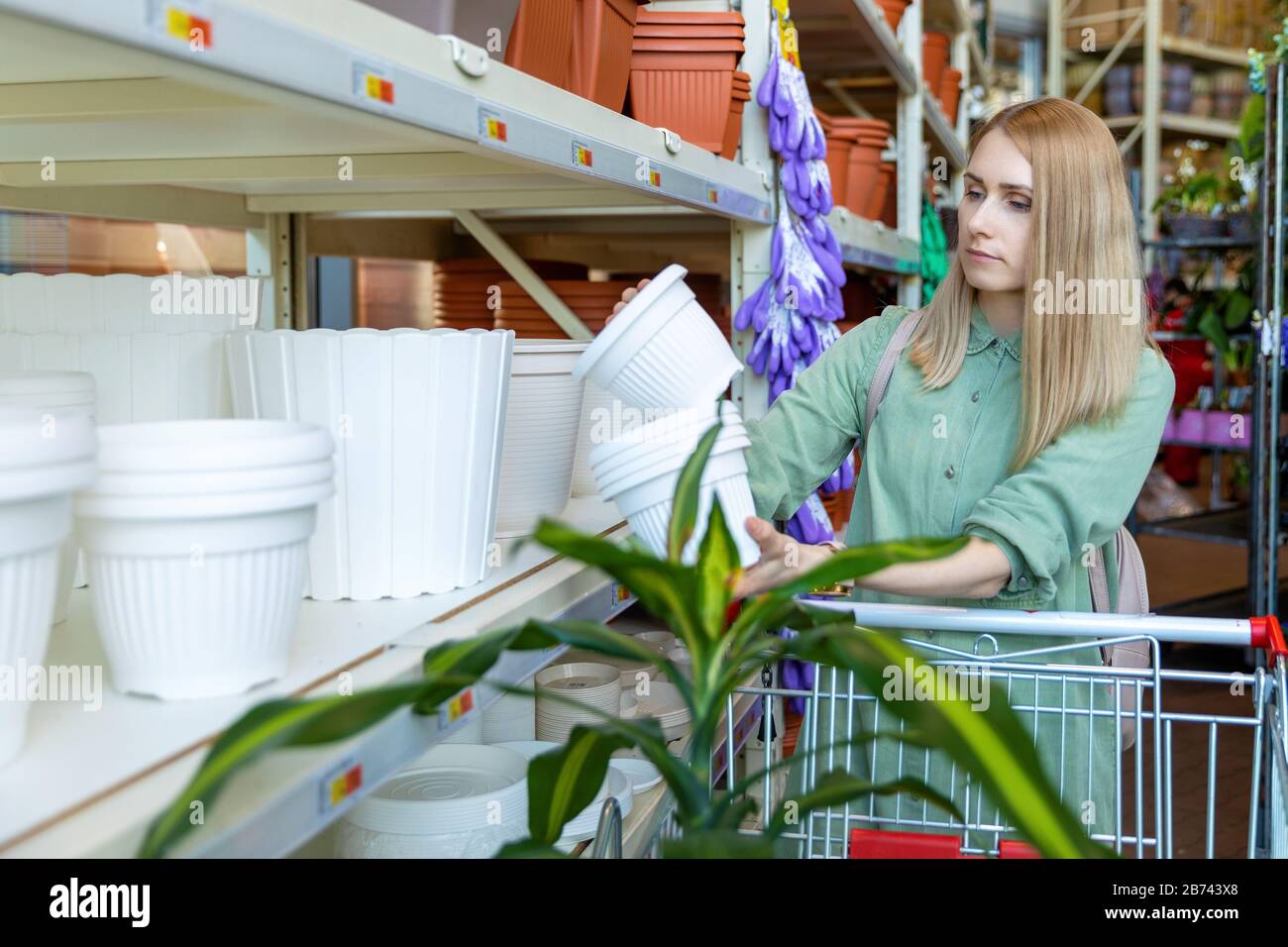 donna che sceglie i vasi di fiore per le piante domestiche al centro del giardino Foto Stock