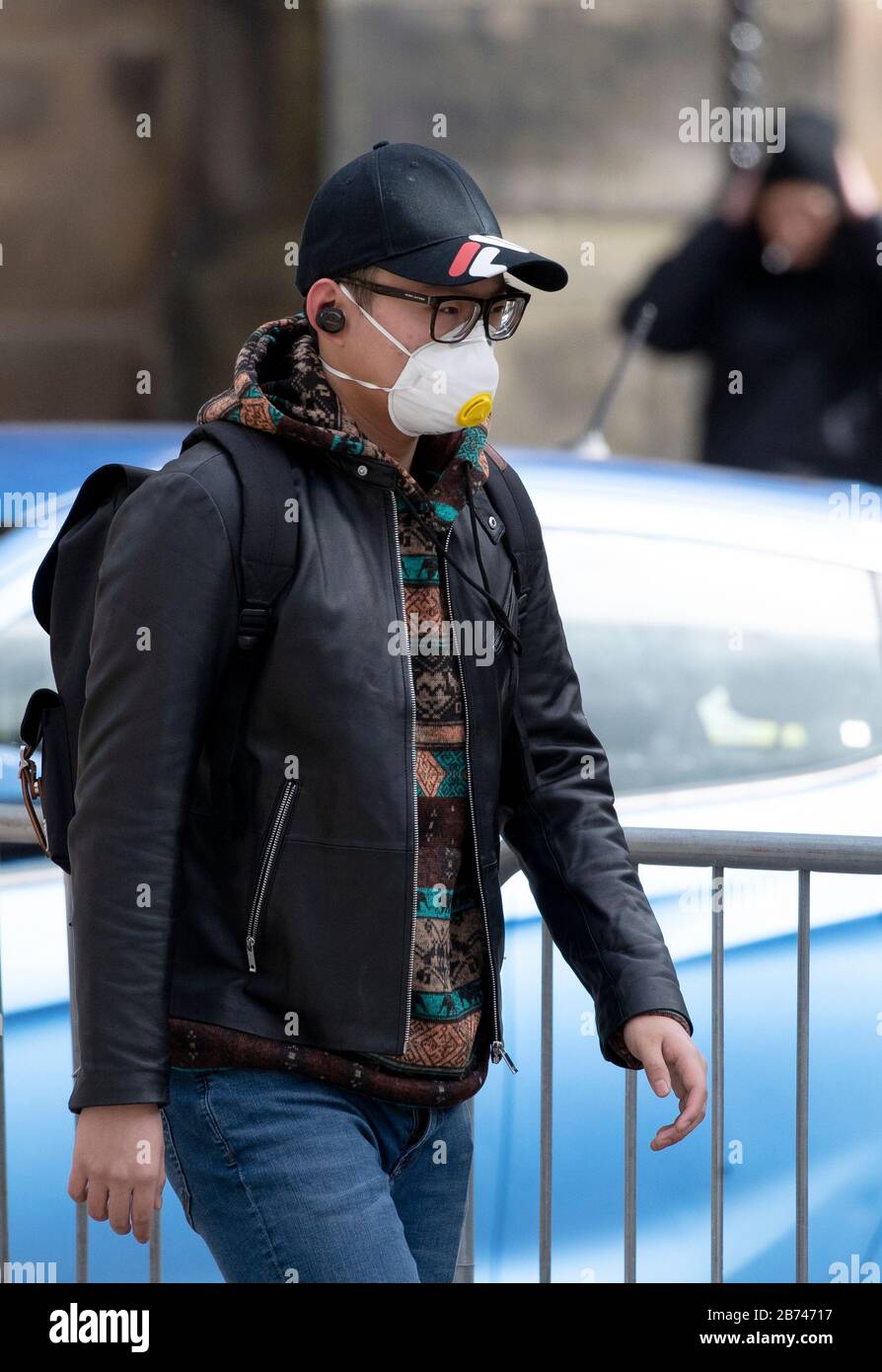 Un uomo che cammina lungo il Royal Mile, Edimburgo, indossa una maschera protettiva per il viso, mentre il miglior scienziato del governo ha riscaldato che fino a 10,000 persone nel Regno Unito sono già infettate. Foto Stock