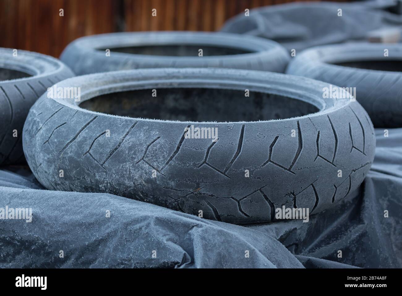 Primo piano di una pila di pneumatici congelati/ghiacciati. Conservato all'aperto durante la stagione invernale. A causa del freddo, completamente coperto di ghiaccio. Pneumatici vecchi. Foto Stock