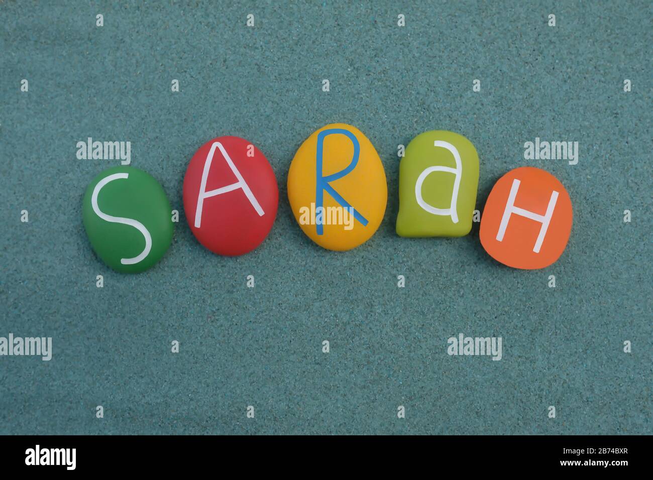 Sarah, femmina nome dato composto con lettere di pietra multicolore su sabbia verde Foto Stock