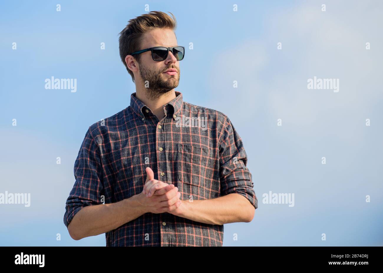 Occhiali da sole alla moda. Modello uomo occhiali esterni blu cielo sfondo. Concetto di protezione ultravioletta. Visione perfetta. Vedere chiaro. Bel ragazzo indossare occhiali da sole. Hipster uomo in occhiali da sole alla moda. Foto Stock