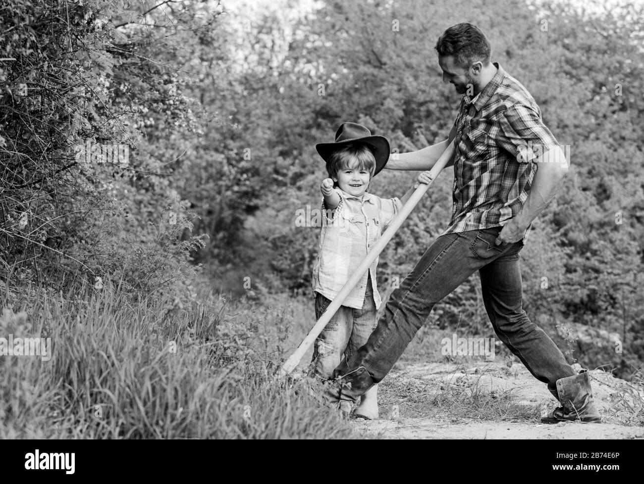 Little Boy e padre nella natura dello sfondo. Spirito di avventure. Little helper nel giardino. Bambino divertirsi cowboy papà. Azienda agricola di famiglia. Vacanze in fattoria dei genitori. Crescente simpatico cowboy. Fine settimana presso l'azienda. Foto Stock