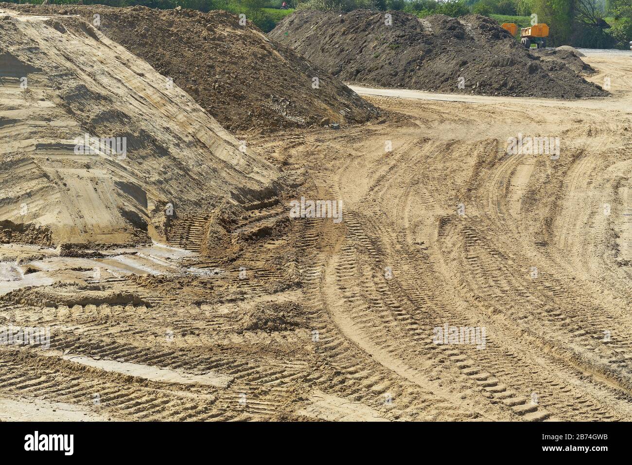 Grande cantiere con pali di terra, sabbia e evidenti tracce di macchinari da costruzione Foto Stock