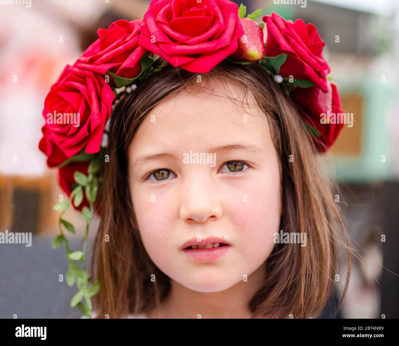 Ritratto di una bambina seria con una corona di rose nei capelli Foto Stock