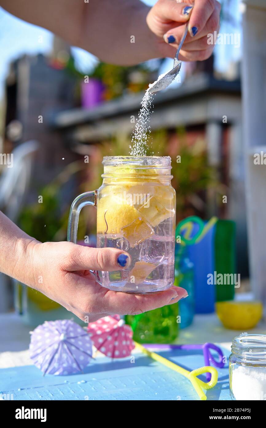 donna che prepara un cocktail, versare lo zucchero nel bicchiere con i pezzi Foto Stock