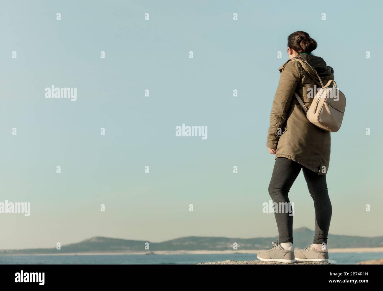Donna con zaino guarda l'orizzonte sul mare Foto Stock
