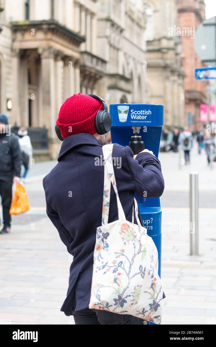Persona che utilizza il punto di ricarica dell'acqua pubblica - Scottish Water Top Tap - Buchanan Street, Glasgow City Centre, Scotland, UK Foto Stock