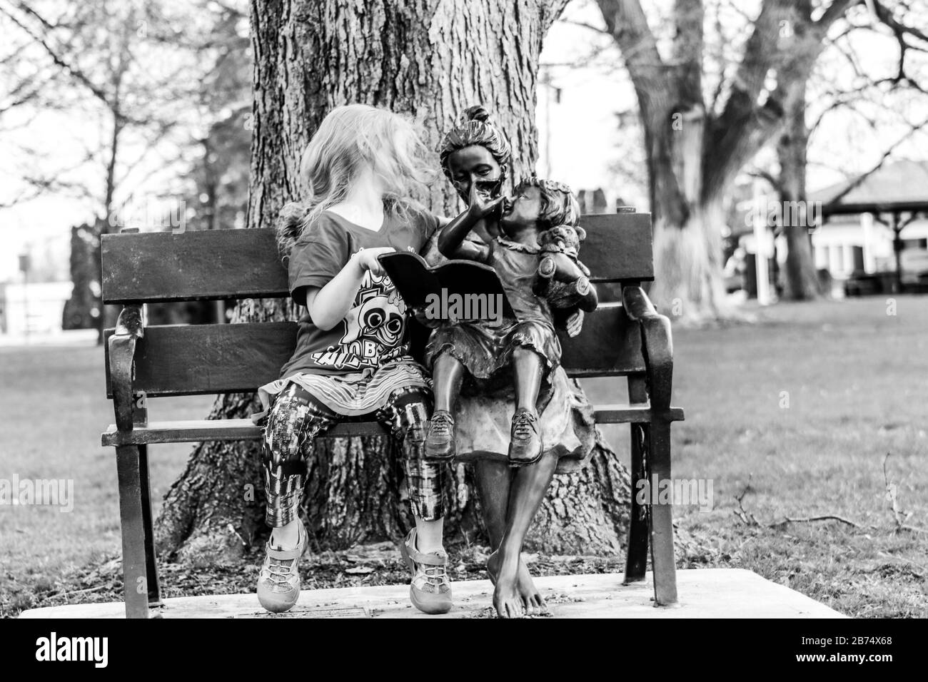 Una bambina seduta su una panchina in un parco. Foto di alta qualità Foto Stock