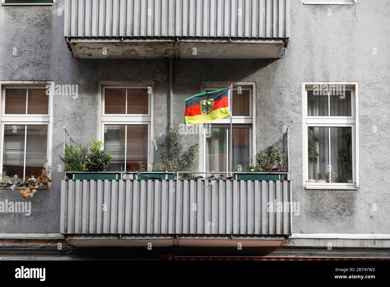 Una bandiera tedesca con aquila federale si affaccia su un balcone di un edificio a Berlino. [traduzione automatica] Foto Stock