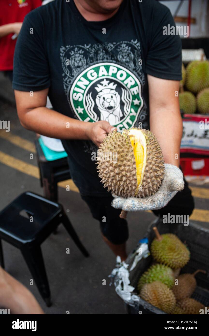 24.02.2019, Singapore, Repubblica di Singapore, Asia - UN venditore apre un durian fresco con un coltello in un mercato di strada a Chinatown. [traduzione automatica] Foto Stock