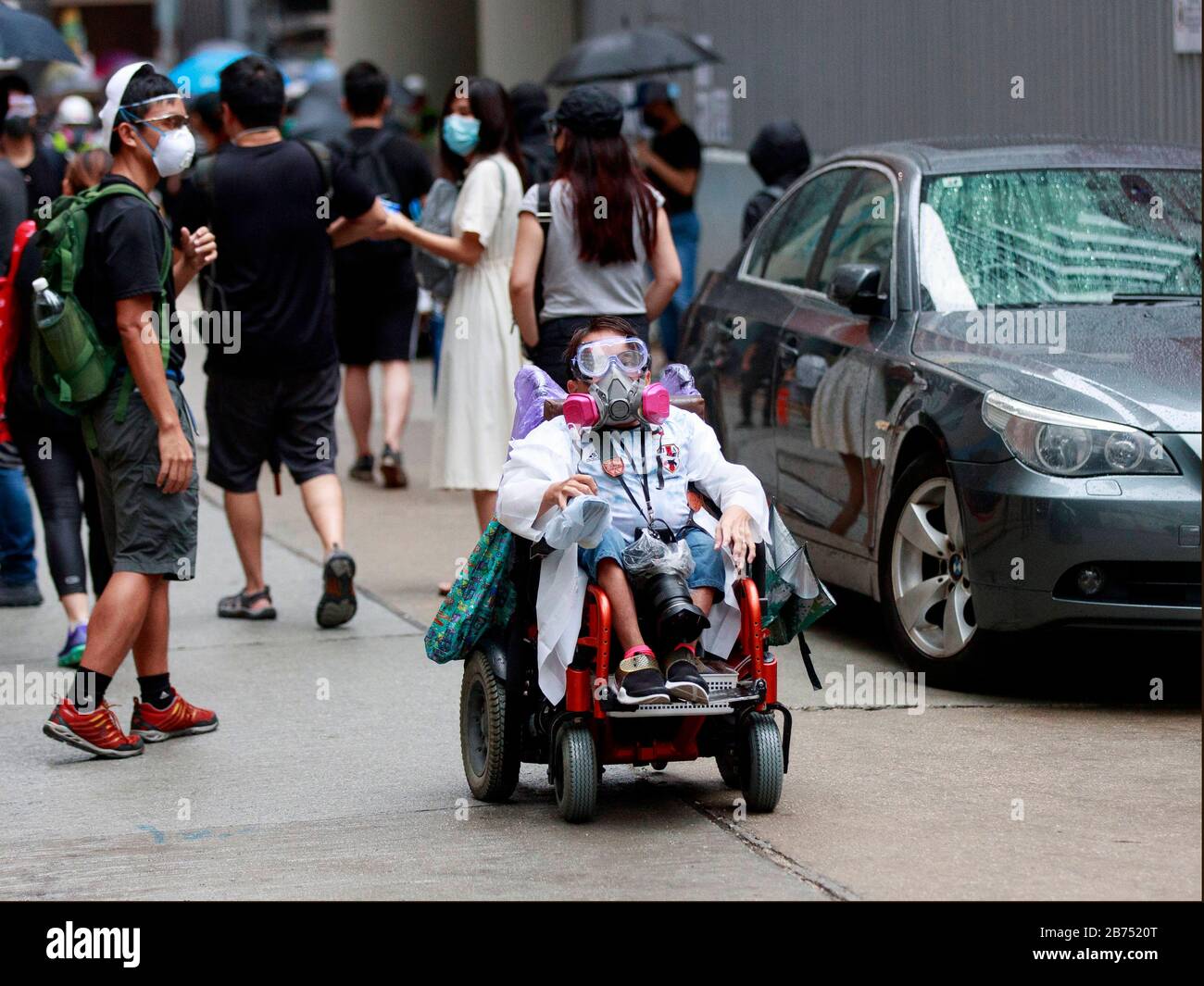 Un fotografo in sedia a rotelle copre la protesta a Wanchai. I manifestanti si radunano contro la legge anti-maschera di Hong Kong. Foto Stock