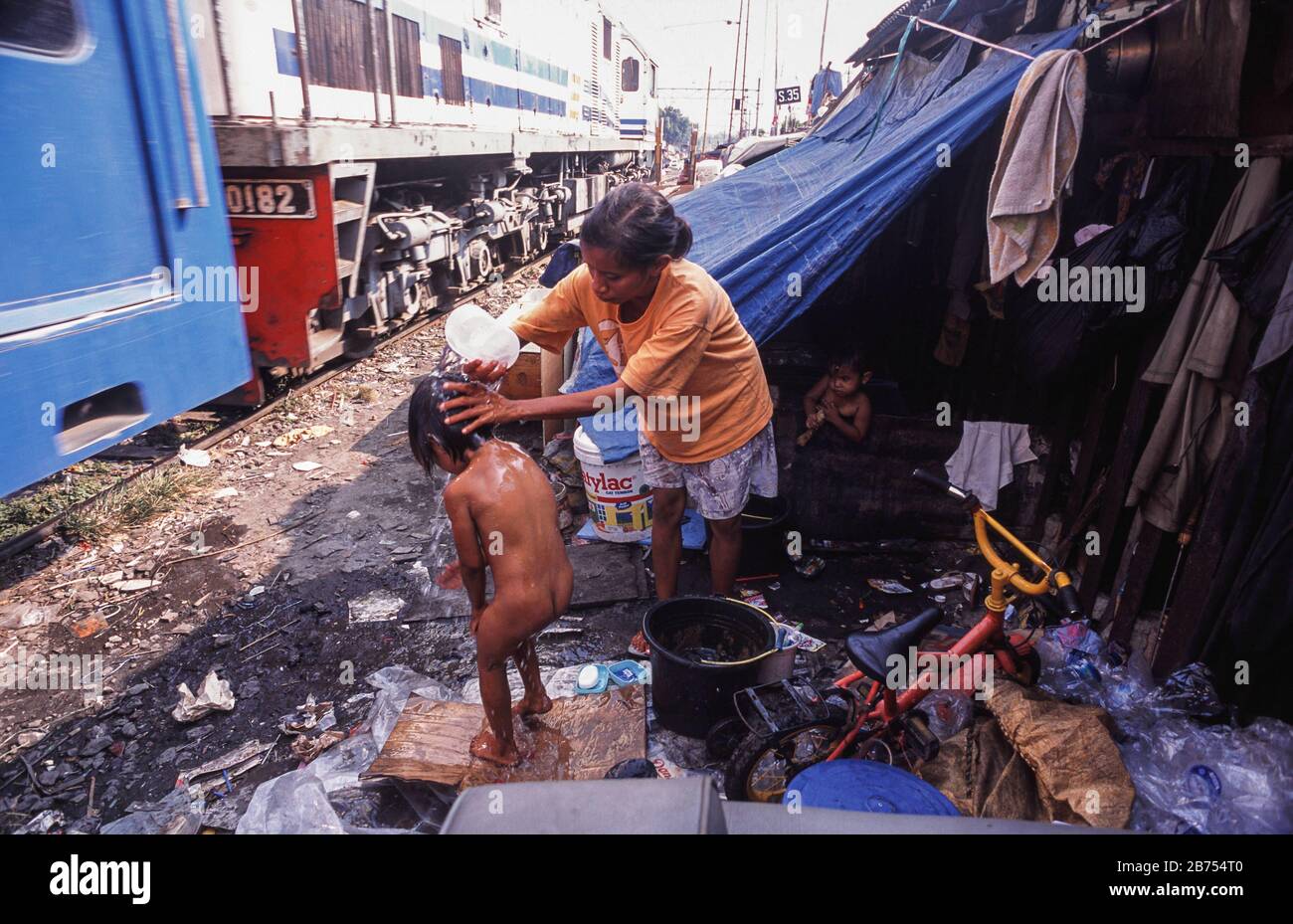 10.08.2009, Jakarta, Java, Indonesia, Asia - UNA madre sta lavando il suo bambino vicino ai binari ferroviari in una zona di baraccopoli della capitale indonesiana. [traduzione automatica] Foto Stock