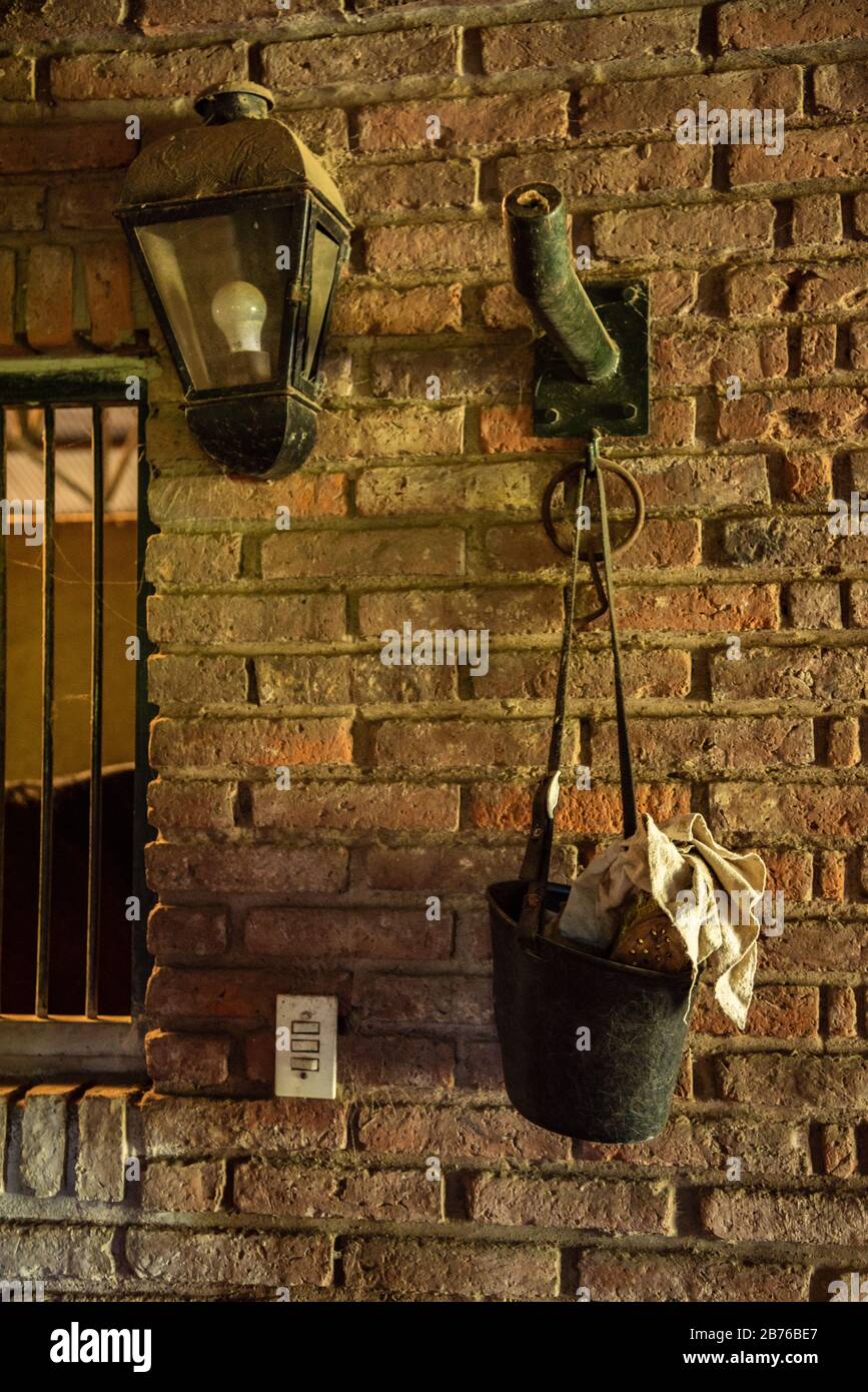 Muro di mattoni con una lampada e un secchio con alcuni tessuti su di esso e un interruttore di luce Foto Stock
