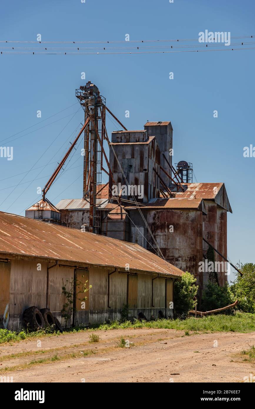 Grande, arrugginito e vecchio macchinario di ferro con fienili o posti di deposito vicino ad una stazione ferroviaria Foto Stock