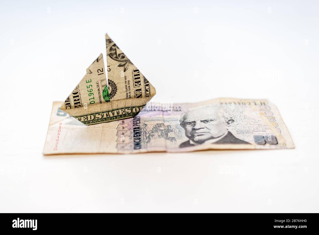 Un dollaro fattura origami barca forma oltre cinquanta pesos fattura, su uno sfondo bianco Foto Stock