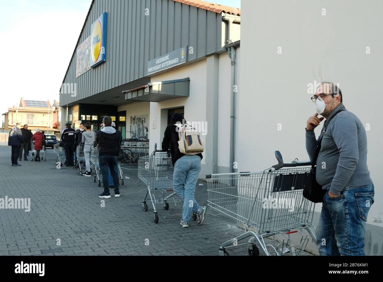 Persone non identificate che indossano maschere protettive nella linea per il supermercato di Catania Foto Stock
