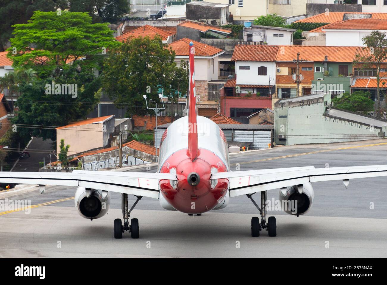 TAM Airlines Airbus A319 sulla pista dell'aeroporto di Congonhas a San Paolo, in Brasile, con case residenziali sullo sfondo. Margini di sicurezza aeroportuali. Foto Stock