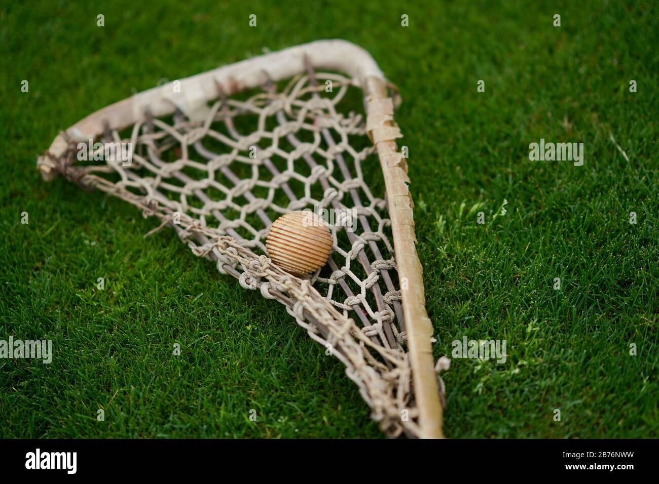 Un vecchio bastone di lacrosse di legno con una palla di legno. Foto Stock