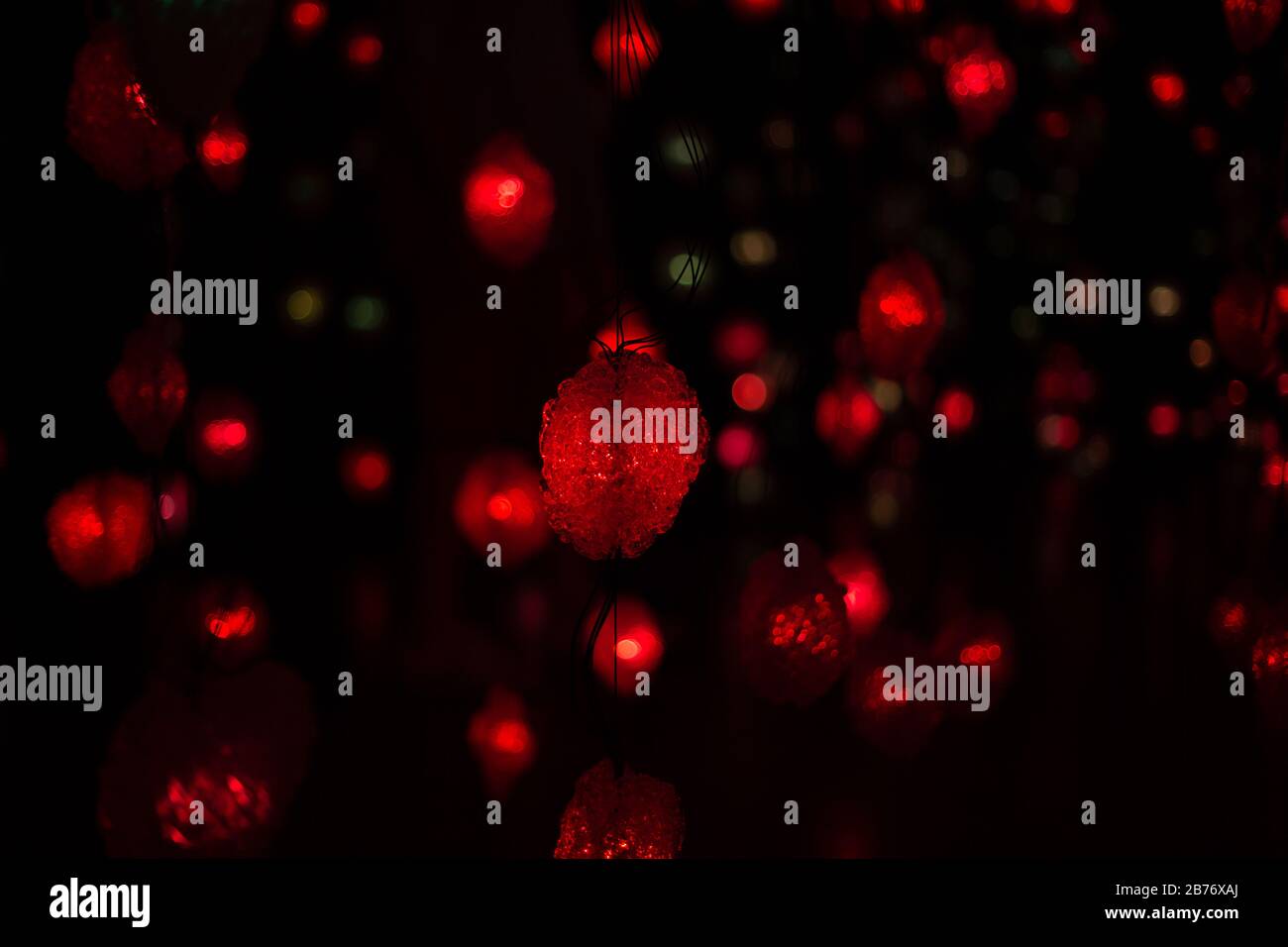 Astratto colorful garlands rosso defocused, blurred bokeh luci effetto texture, sfondo. Forme arrotondate sfocate rosse. Sfondo modello universale. Sfocatura Foto Stock