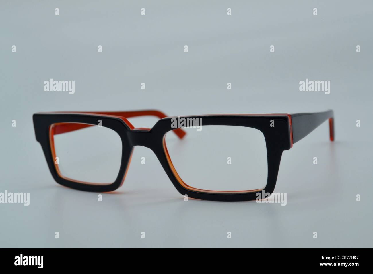 Paio di eleganti e moderni occhiali da lettura con bordo nero e luce arancione in isolamento Foto Stock