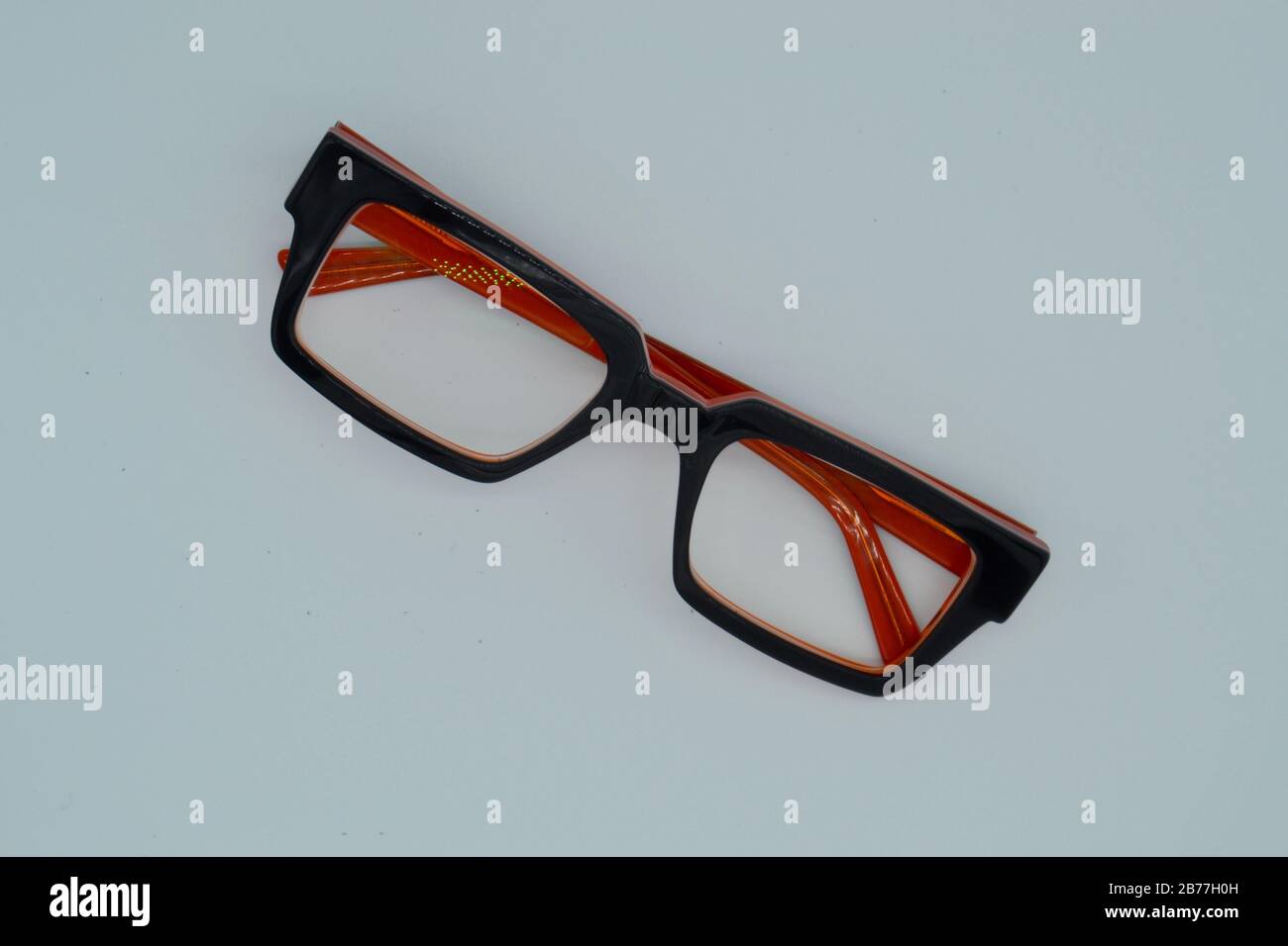 Paio di occhiali da lettura con bordo nero pesante ripiegati su sfondo bianco Foto Stock