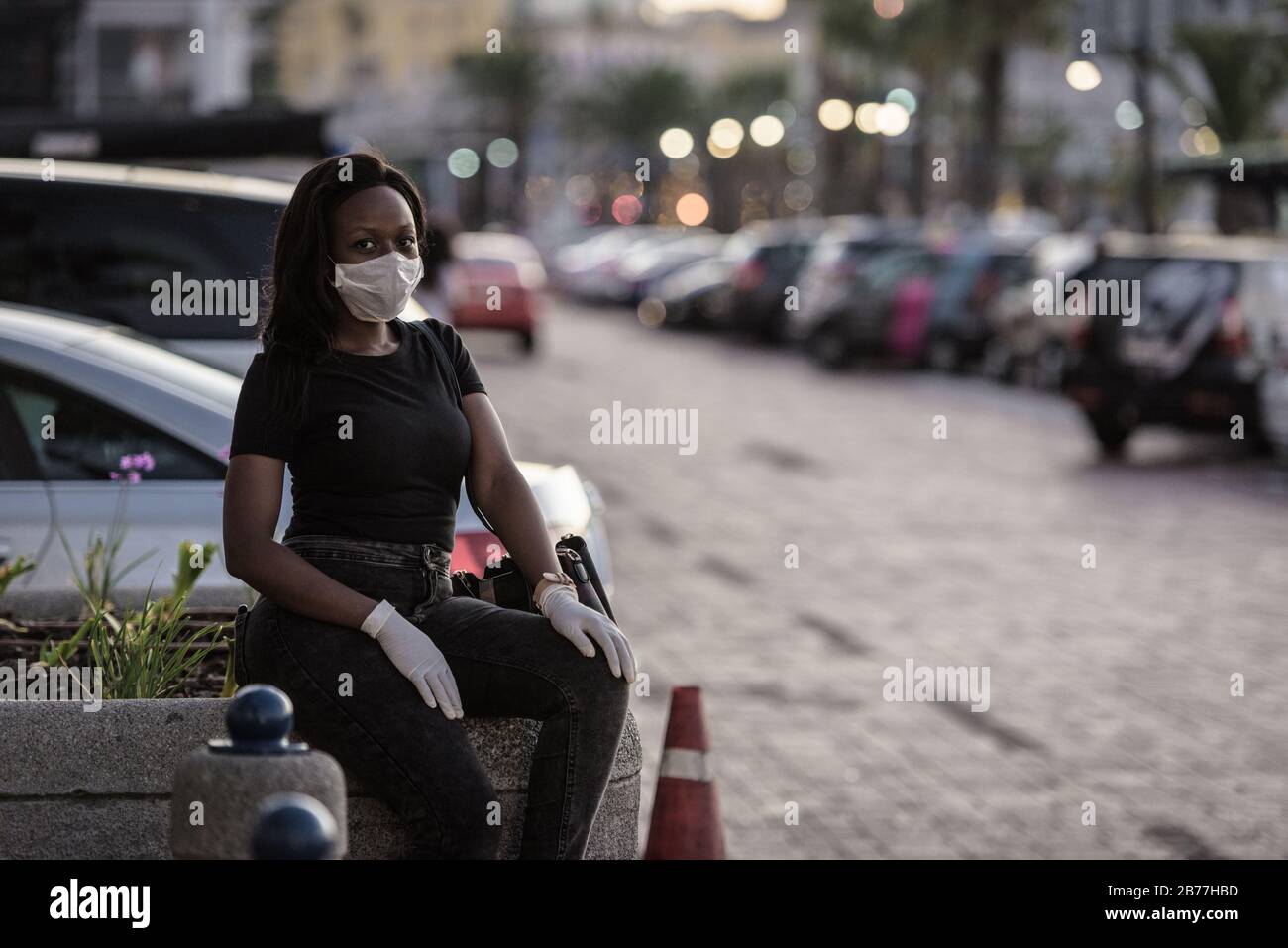 Portia Mkhwanazi è una delle poche persone che indossano maschere e guanti dalla pandemia di coronavirus nella popolare città turistica sudafricana di Città del Capo Foto Stock